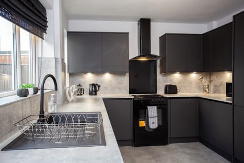 Cook in style in this sleek, modern kitchen featuring dark cabinetry, under-cabinet lighting, and all the essentials for a convenient and comfortable stay.