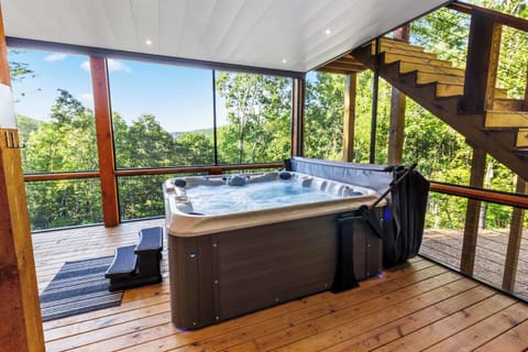 The screened-in deck features a 7-person saltwater hot tub with stunning forest and mountain views. The deck has a finished ceiling for all-weather use, providing a perfect spot to relax and unwind.