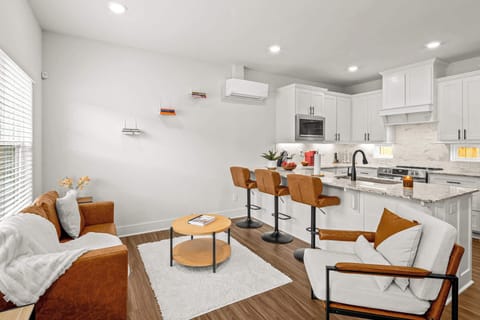 Bright open‑concept living area with comfy sofa, smart TV and kitchen island with bar stools—perfect for relaxing or chatting while you cook.