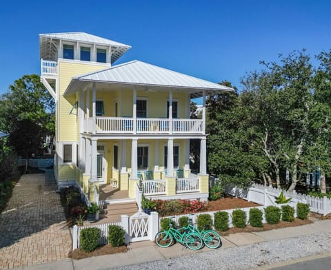 Charming beach house with wraparound porches, tower lookout, and coastal-style architecture in a peaceful neighborhood setting.