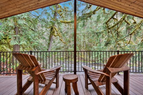 Relax in rustic Adirondack chairs on your private covered deck, surrounded by towering moss-draped trees and peaceful forest views that make every moment feel like an escape.