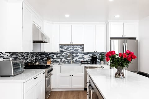 - Modern kitchen with bright white cabinets and stylish backsplash  
- Stainless steel appliances and farmhouse sink for easy cooking  
- Fresh roses add charm to the open kitchen and island design