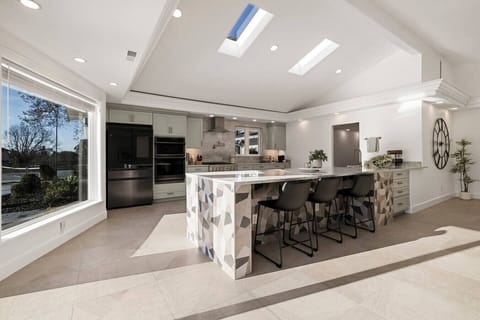 Bright, modern, and built for gatherings! This stunning kitchen features a geometric island, sleek appliances, and skylights that fill the space with natural light.