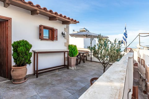 The roof terrace of Casa Eleni features a dining table for outdoor meals and a washing machine for convenience, all set against an open-air backdrop.