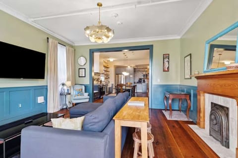 Living room with a comfortable couch, smart TV, and a small workspace with a desk and chair — perfect for relaxing or getting work done.