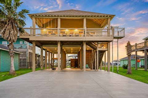 Elevated coastal vacation home with spacious covered parking, wraparound deck, and beachside location in Bolivar Peninsula, Texas.