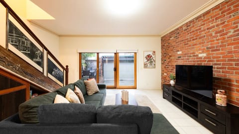 Exposed Brick Charm: Cozy living area featuring a striking brick feature wall and warm timber-framed glass doors.