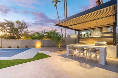 Outdoor bar with seating, grill, and shade for effortless entertaining.