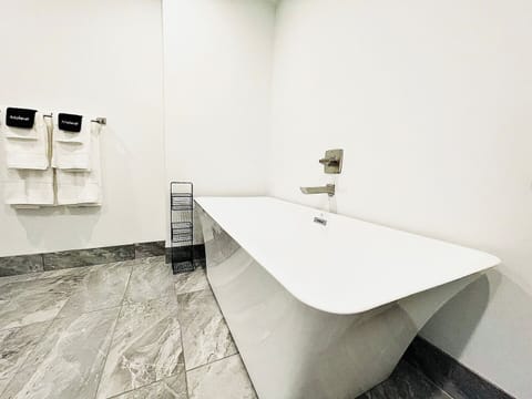 A sleek and modern bathroom showcasing a luxurious freestanding soaking tub, marble floors, and minimalist decor for a spa-like retreat. Perfect for unwinding in style and comfort.