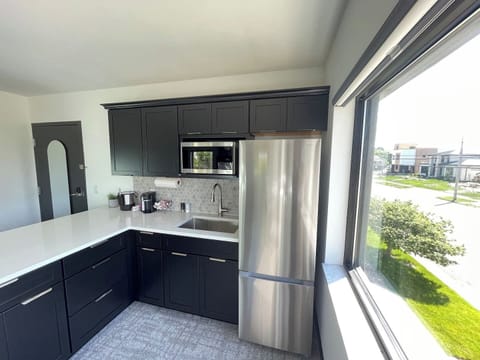 Fully equipped with stainless steel appliances and sleek cabinetry, this kitchen is perfect for preparing meals while enjoying natural light streaming through the large windows.