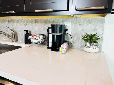 A close-up of the modern kitchen featuring a stylish backsplash, stainless steel sink, and coffee station.

