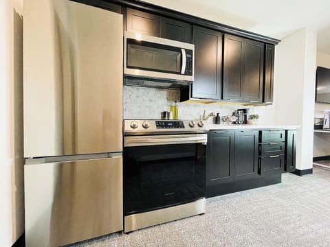 A modern kitchen equipped with stainless steel appliances, dark cabinetry, and a spacious countertop perfect for meal prep. Complemented by stylish decor, this kitchen is both functional and inviting for your culinary adventures.