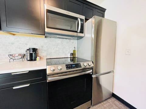 Stylish kitchen with dark cabinetry, stainless steel appliances, and a well-appointed coffee station for your morning needs.