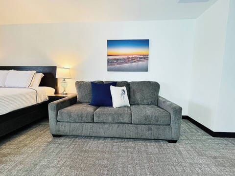 A comfortable sofa with vibrant throw pillows, situated next to a cozy bedroom for added relaxation space.