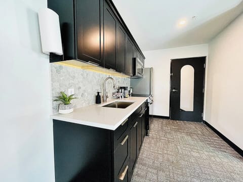 Stylish kitchen with dark cabinetry, stainless steel appliances, and a well-appointed coffee station for your morning needs.