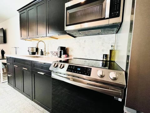 Stylish kitchen with dark cabinetry, stainless steel appliances, and a well-appointed coffee station for your morning needs.