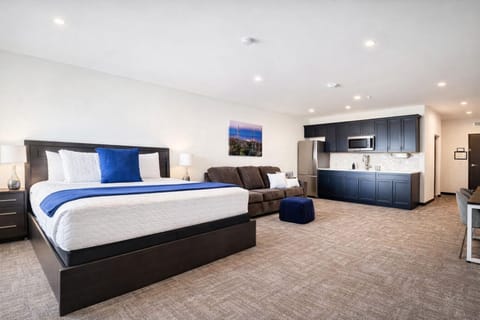 A bright, open room featuring a comfortable bed, work desk, ample storage, and a large TV, perfect for relaxing or working during your stay.