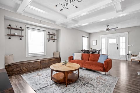 Step into our modern living room with industrial shelving and lighting. Featuring a comfy couch, thoughtful decor, and a smart TV for your convenience. 