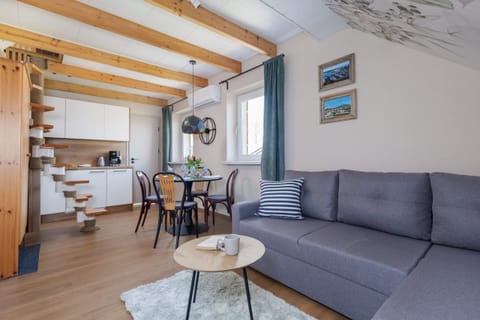 A cozy living room with a gray sofa, wooden beams, and a bright, inviting atmosphere.
