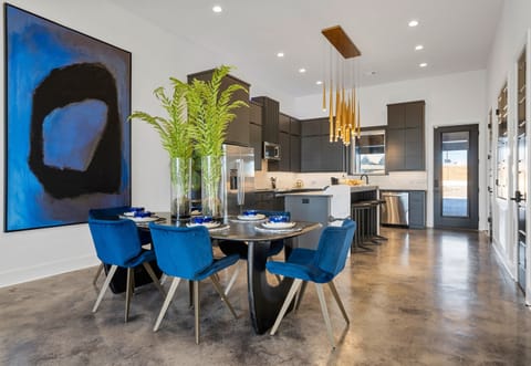 This vibrant dining space combines bold blue chairs, lush greenery, and elegant lighting, creating a stunning and inviting setting for memorable meals.