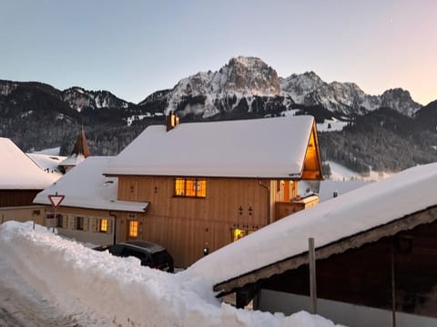 The snow-covered charming chalet offers breathtaking views of the Alps.