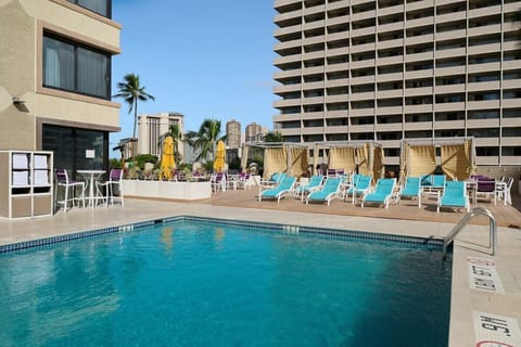 Dive into a refreshing swim beside loungers and palms.