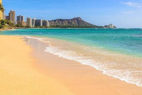 Stroll along soft sand with turquoise water and skyline views.