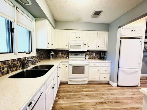 Spacious kitchen with white cabinets, modern appliances, and a stylish backsplash, offering ample space for meal preparation.