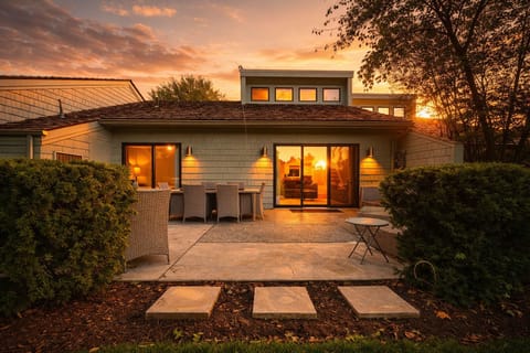 A serene backyard with a spacious patio, outdoor dining, and beautiful greenery, perfect for relaxing evenings.