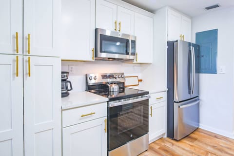 The kitchen features a stainless steel refrigerator, electric range and microwave.