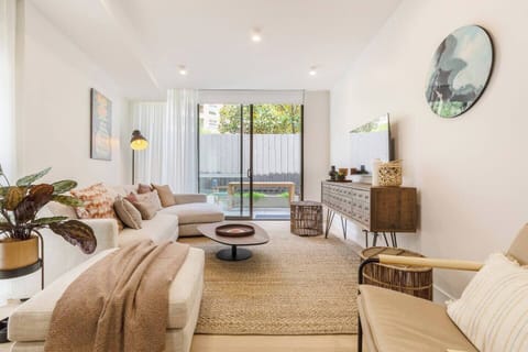 Relax in the bright, inviting lounge room with natural light, cosy seating, stylish wall art, and a TV - perfect for unwinding after an outdoor meal on the patio.