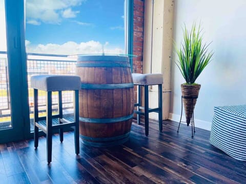 A unique and rustic bar table crafted from a barrel, paired with upholstered stools. Situated by the floor-to-ceiling windows, offering scenic views and a cozy spot for drinks or conversation.

