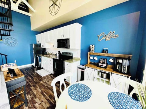  Modern kitchen with white cabinetry and appliances, coffee bar, and paired with a charming dining area. Large windows provide stunning views of the waterfront.