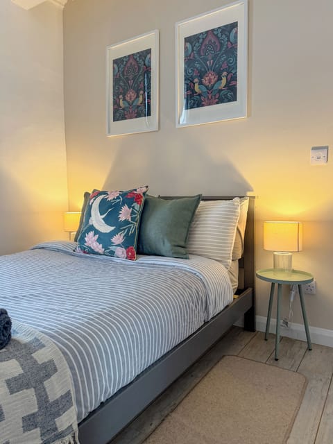 Serene double bedroom with soft lighting, chic art, and plush bedding.