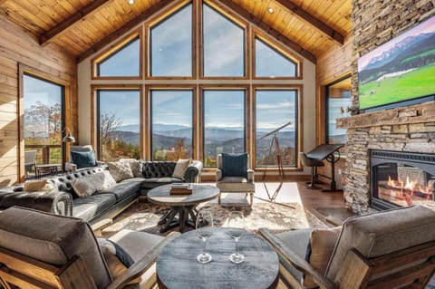Spacious Living Room with Soaring Windows, Cozy Fireplace & Breathtaking Mountain Views.