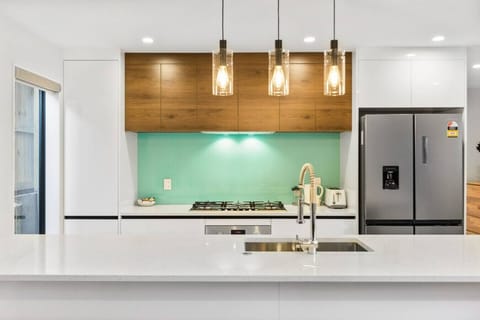 White modern kitchen with touch of green, highlights the stainless steel appliances and wooden cupboards.
