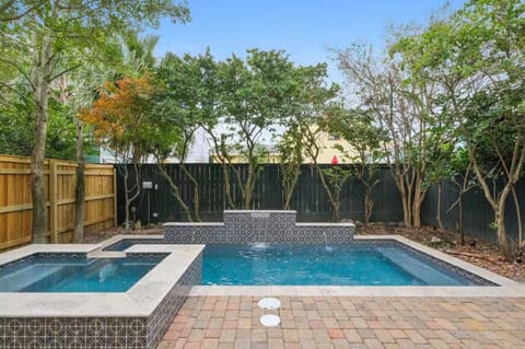 Private backyard with a sparkling pool and hot tub surrounded by lush greenery — your own quiet retreat right in the city.