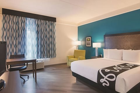 Relax in a sunlit room with desk, TV, and plush bed.