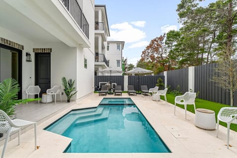 A stylish and inviting outdoor pool and spa, comfortable lounge chairs, lush greenery, and ambient lighting for relaxation and entertainment.