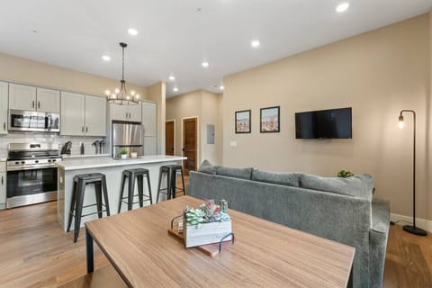 this living and dining space offers a cozy couch, a smart TV, and a dining table with bench seating.