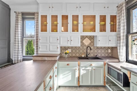 The white cabinets paired with green countertops create a stunning contrast that makes cooking feel like a joy.