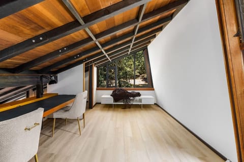 Cozy up with a view! This charming loft nook features warm wood accents, a comfortable seating area, and panoramic windows overlooking serene natural landscapes.