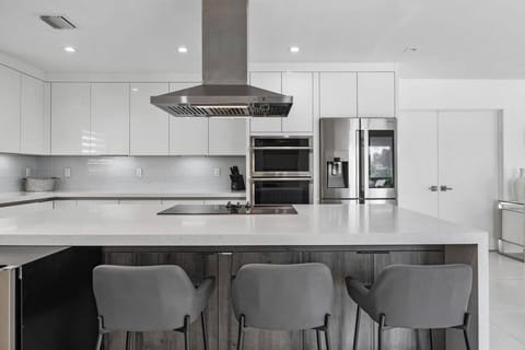 Contemporary culinary space with premium white cabinetry and sleek breakfast bar