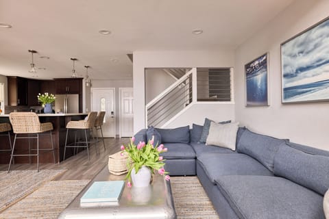 View of the living room, open plan kitchen, bar/eating area, and front door entry.