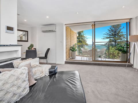 Unwind in the spacious living room, where lush treetops and glimpses of the sea create a calm and welcoming place to relax.