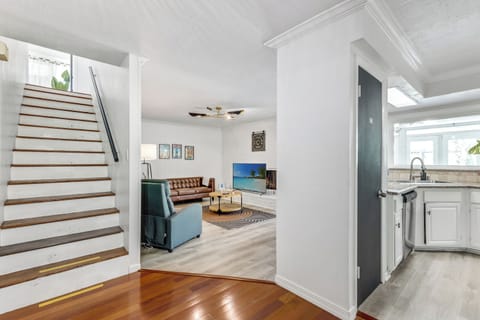 Open living area with stairs, modern seating, and bright kitchen view.