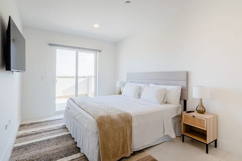 Rest easy in a cozy king sized bed with fresh linens and calming, minimalist decor - Wake up to natural light streaming through floor to ceiling glass doors - Serene bedroom is your perfect retreat for peaceful nights and mornings