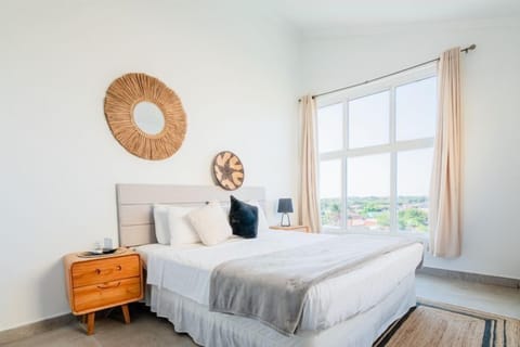 Enjoy a serene night's rest in this bright and inviting bedroom featuring a king sized bed and cozy decor - Wake up to natural sunlight pouring in through large windows - Peaceful retreat with thoughtfully chosen accents for a calm atmosphere