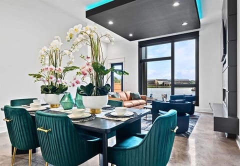 Gather around this vibrant dining area, complete with stylish seating, chic lighting, and large windows that flood the room with natural light for a welcoming ambiance.