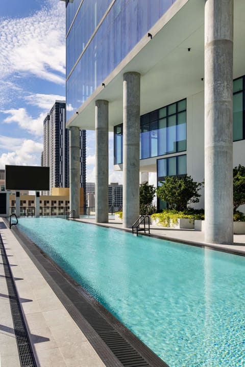 Long outdoor pool beside a high-rise building.